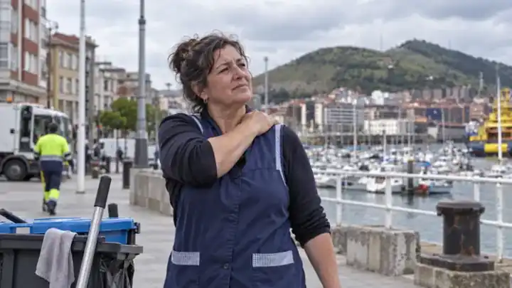 Trabajadora en el paseo marítimo tocándose el hombro