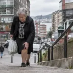 Mujer mayor subiendo unas escaleras con bolsas de compra