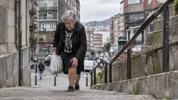 Mujer mayor subiendo unas escaleras con bolsas de compra