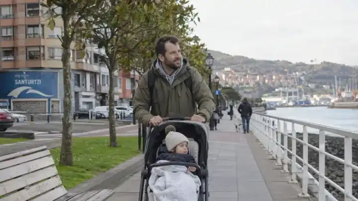 Padre paseando con un niño en carrito junto al mar