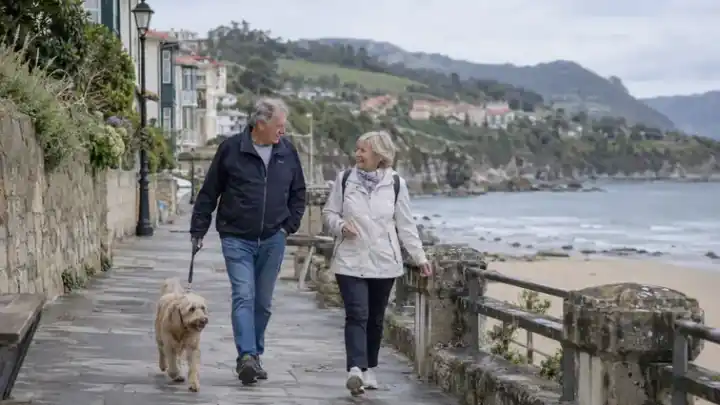 Pareja mayor paseando con su perro junto al mar