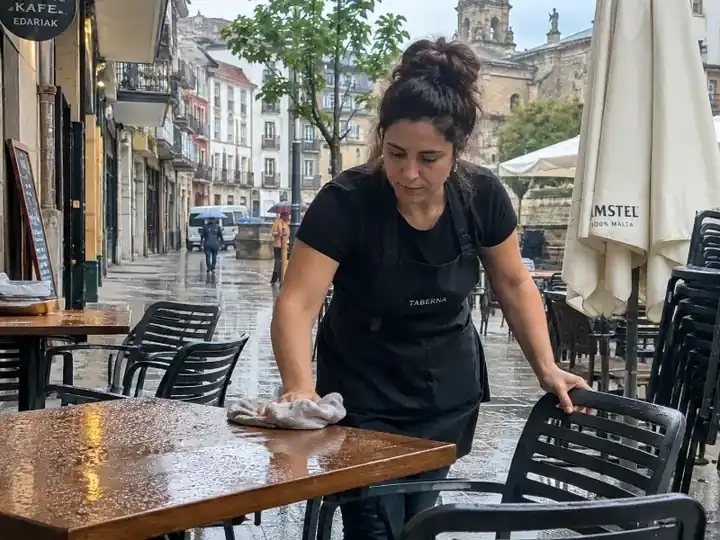 Trabajadora limpiando una terraza mojada después de la lluvia