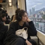 Mujer joven sentada en el transporte público mirando por la ventana