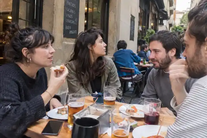Grupo de amigos sentados tomando pintxos y charlando