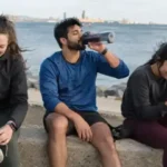 Tres jóvenes descansando junto al mar después de correr