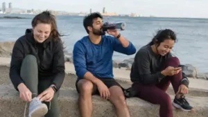 Tres jóvenes descansando junto al mar después de correr