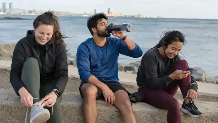 Tres jóvenes descansando junto al mar después de correr