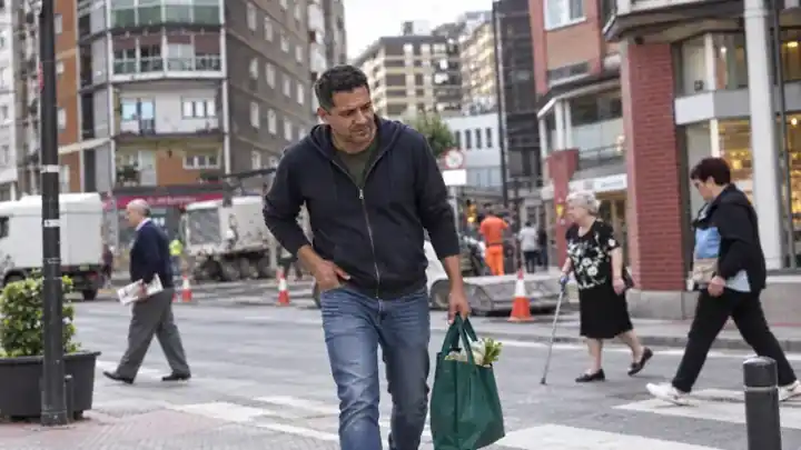 Hombre caminando por la calle con una bolsa de compra